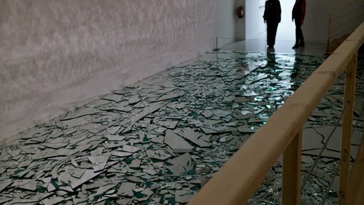 Broken glass scattered on the floor of the gallery space