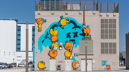 Wall art of orange cartoon characters creating graffiti art