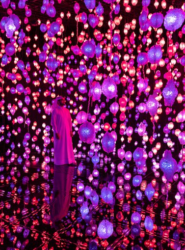 A gallery display at the National Museum of Qatar of hanging lights in pink, purple and red.