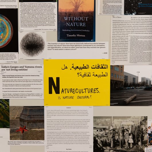 A collection of documents surround a yellow paper in the middle that has the word 'Naturecultures' written on it.