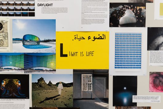 A collection of documents surround a yellow paper in the middle that has the word 'Light is Life' written on it.