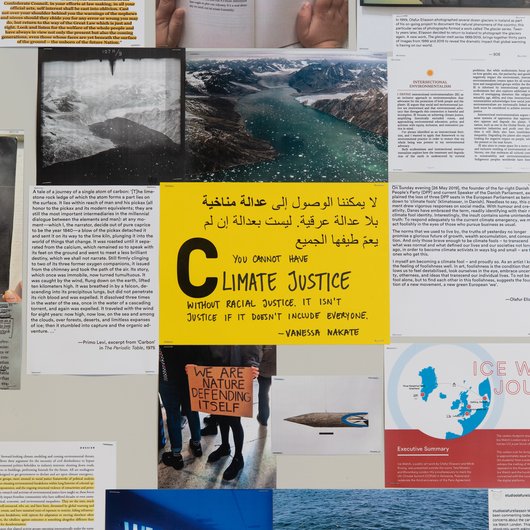 A collection of documents surround a yellow paper in the middle that has the word 'Climate Justice' written on it.