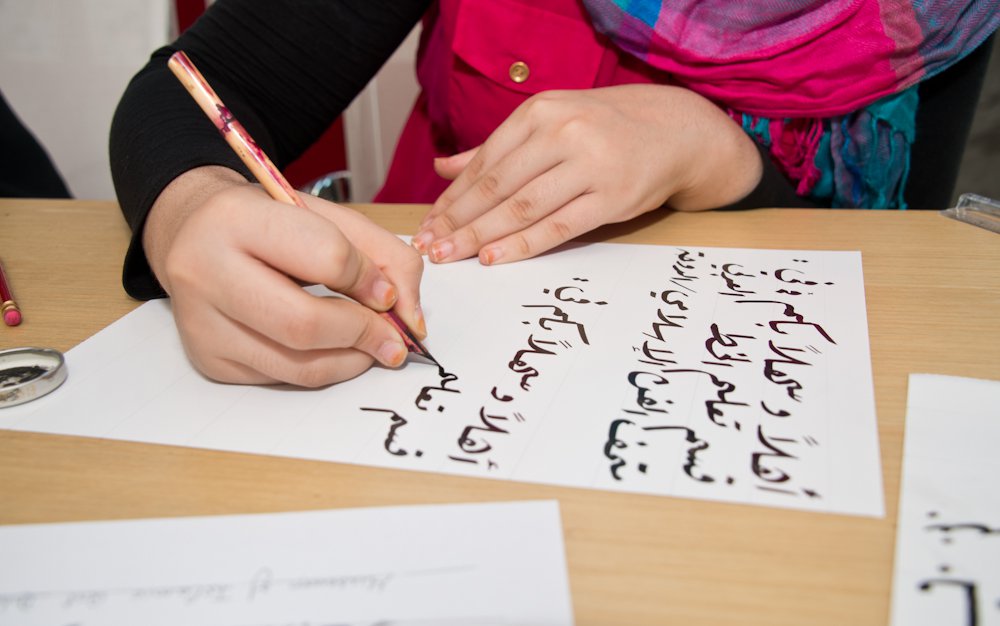 A close up shot of a student practicing Arabic calligraphy