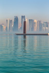 A portrait shot of Richard Serra's sculpture '7' located at MIA against Doha's iconic skyline