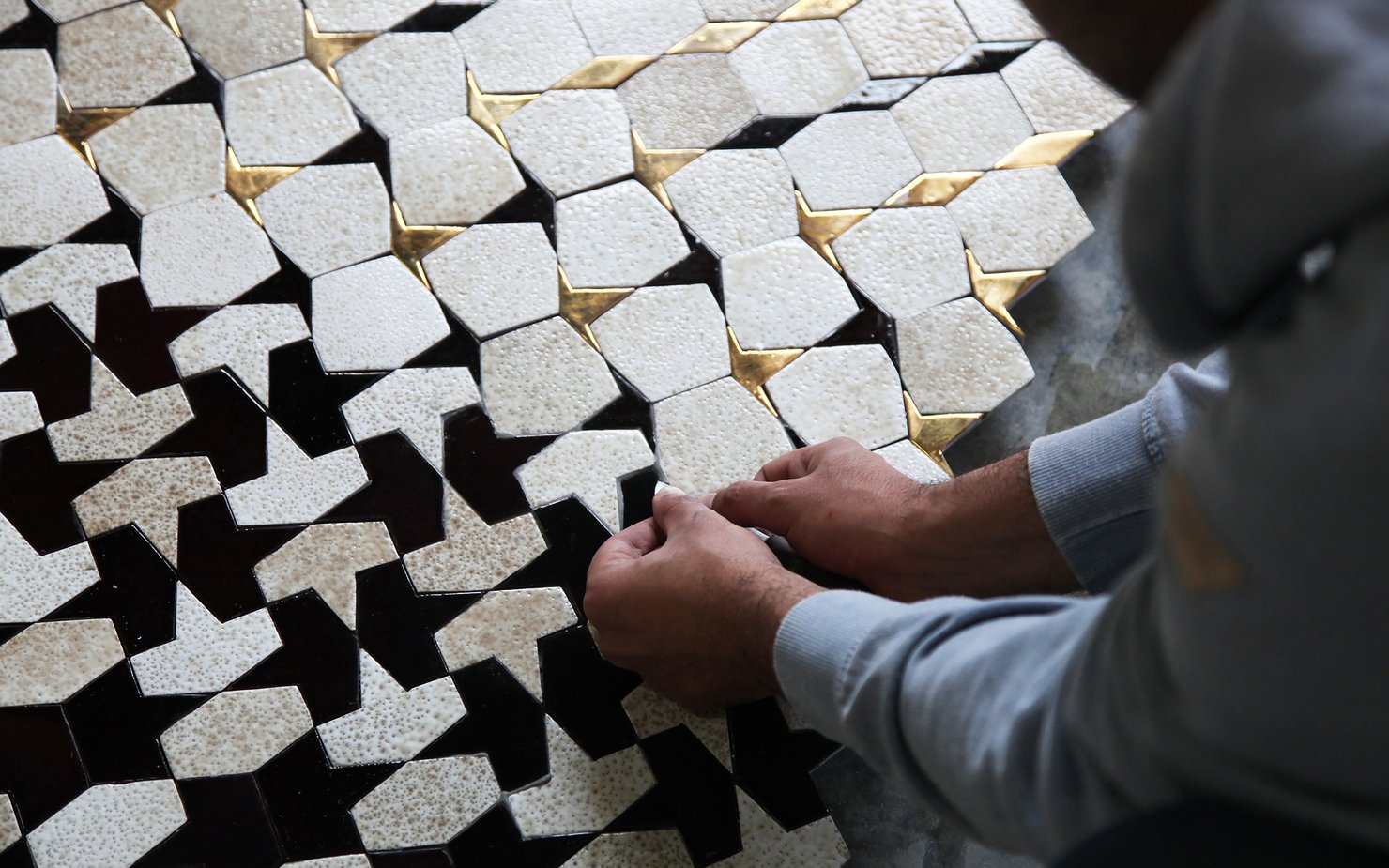 Artisan laying tiles in geometric pattern