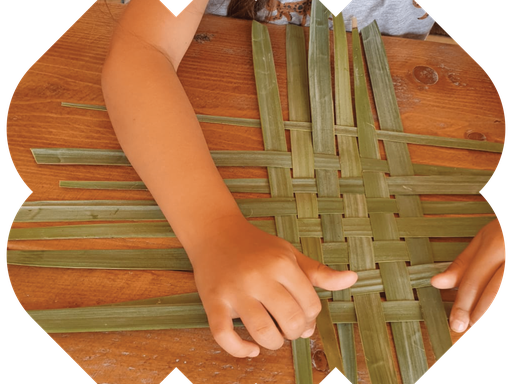 Kid weaving natural palm fronds on a wooden table