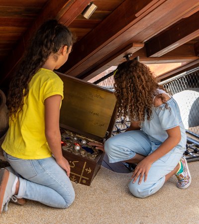 Two young girls search through a box as they look for treasure