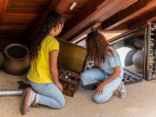 Two young girls search through a box as they look for treasure