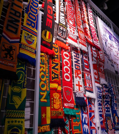 Photo of multiple, colourful football scarves hanging on a white, caged, frame.