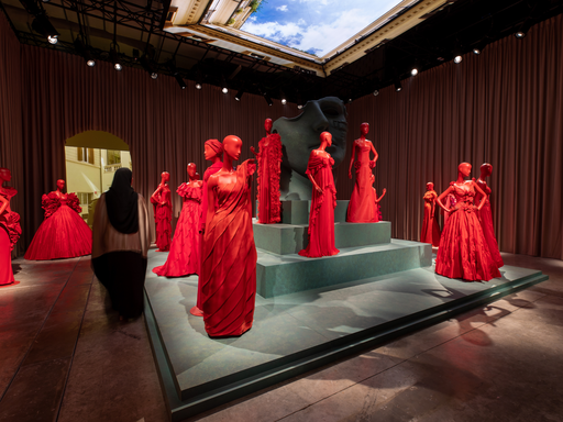 Woman walking in a exhibition full of red dresses