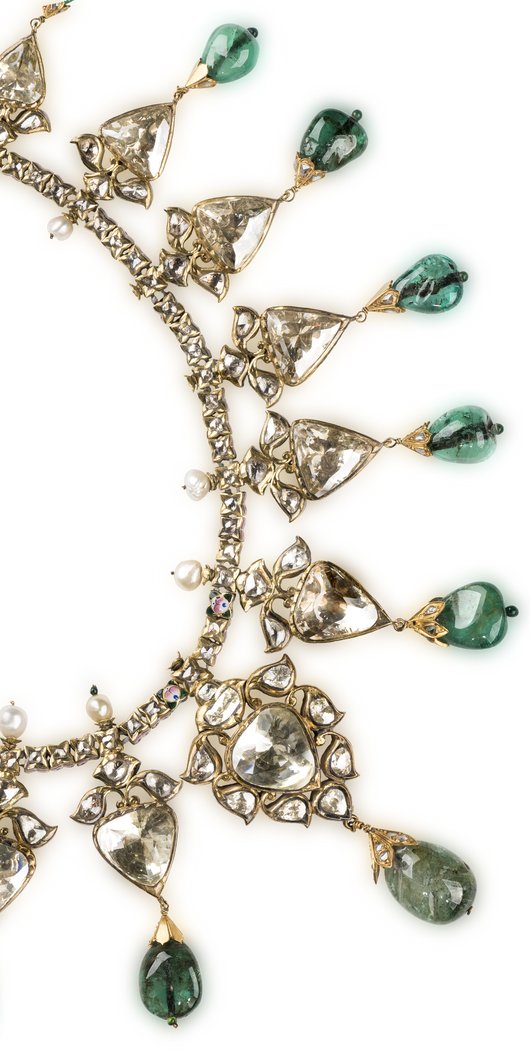 A gold necklace with large diamonds and emeralds