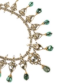A gold necklace with large diamonds and emeralds