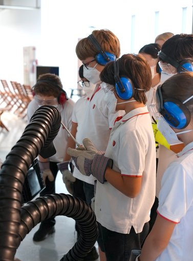 Kids wearing protective mask running a machine