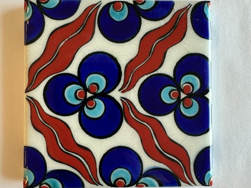 A piece of square tile with painted with abstract shapes