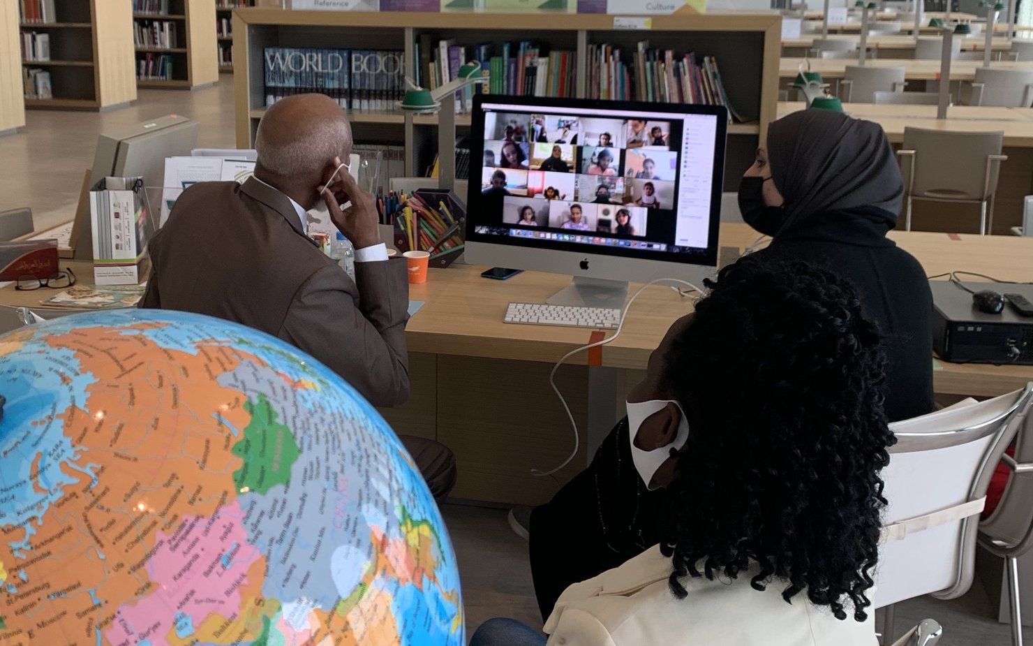 رجل وامرأة يجلسان أمام جهاز كمبيوتر داخل متحف الفن الإسلامي ويستضيفان فعالية كوكب الأطفال عبر برنامج زووم