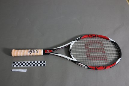 مضرب تنس من شركة، ويلسون، بالألوان الأسود والأحمر والأبيض، يحمل توقيع لاعب التنس الشهير روجر فيدرر