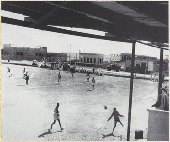 صورة بالأبيض والأسود للاعبي كرة القدم على أرض ملعب واسعة.