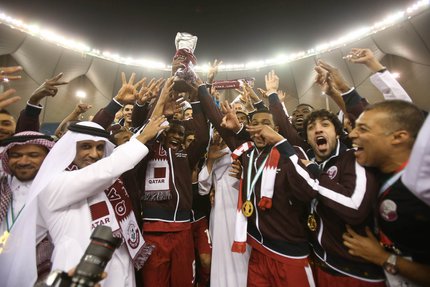 The Qatar football team show raising a trophy in celebration.