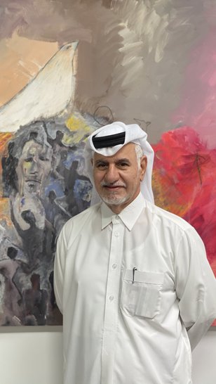 Ruwad Artist Hassan Al-Mulla standing next to his paintings in his studio at the Fire Station.