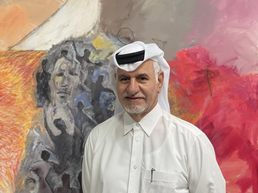 Ruwad Artist Hassan Al-Mulla standing next to his paintings in his studio at the Fire Station.