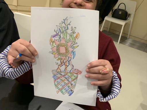 A girl with autism holds a drawing of her creation in her hand