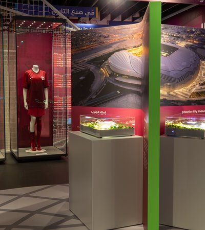 A museum display with maroon football kitted mannequins behind glass and a model of a stadium with the words Education City Stadium visible.