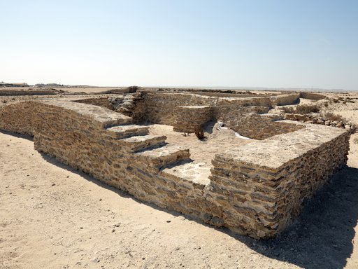 A stone structure on a beach with a visible set of stairs.