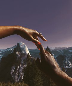 Two hands touching with a mountain landscape in the background.