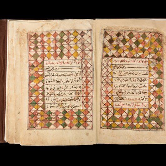 A photo of the Al Zubarah Qur’an on a black background, showing the first two pages and the decorations that adorn them