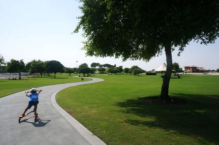 Aspire Park with a child riding his scooter on a pathway surrounded by green patches and trees