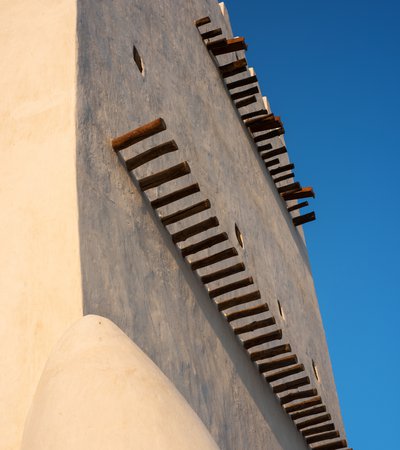 A close-up view of Barzan tower showing its white walls and protruding wooden shafts