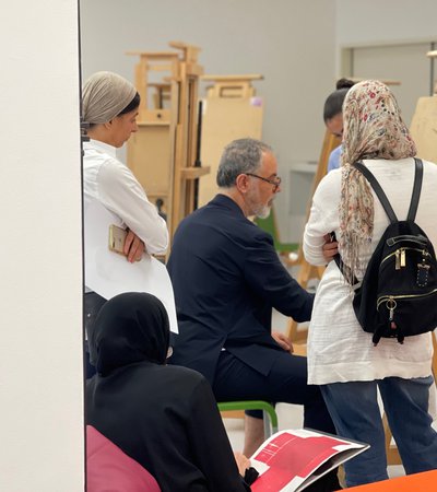 People observing Ismael Azzam as he is demonstrating a work on canvas stand