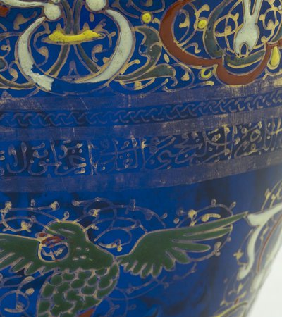 Details of a blue ceramic pot painted with gold Arabic letters and Islamic designs
