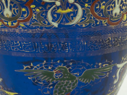 Details of a blue ceramic pot painted with gold Arabic letters and Islamic designs