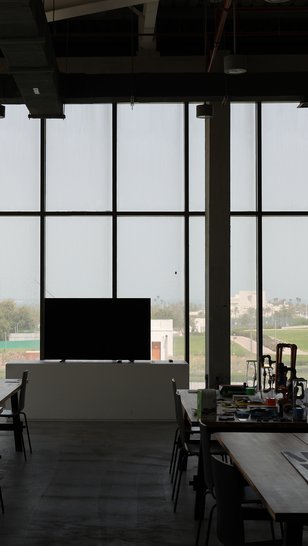 Education Studio at Fire Station with tables, a TV screen and panoramic windows with a view of Al-Bidda park.