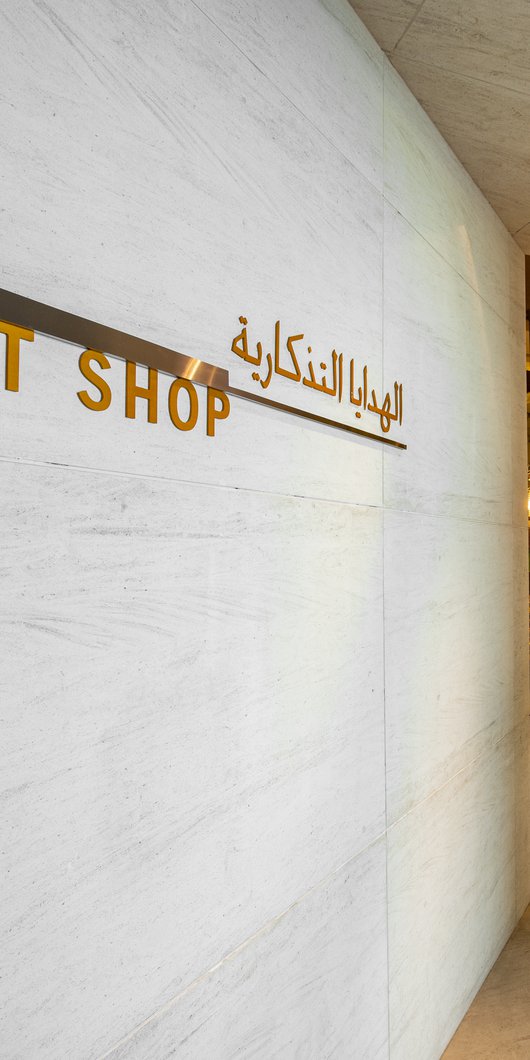 مشهد داخل متجر الهدايا في متحف الفن الإسلامي يٌظهر حائطاً عليه لافتات ومدخل المتجر في الخلف.