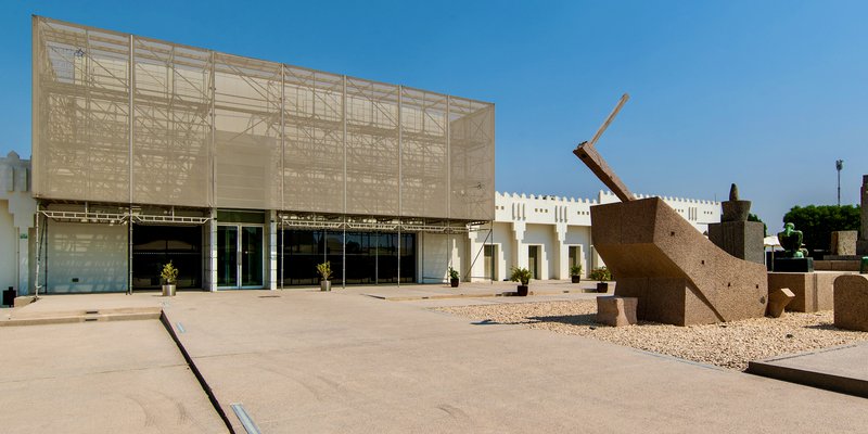 Exterior view of Mathaf entrance with large stone sculptures