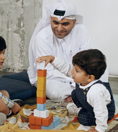A father and his two young sons playing with building blocks at Dadu, Qatar Children's Museum