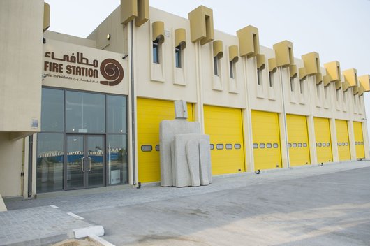 Exterior of The Fire Station Artist in Residence building showing its bright yellow shutter doors and sculpture at the entrance