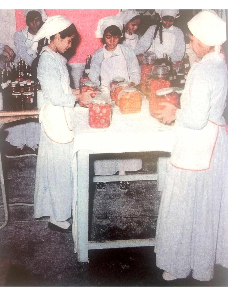 Old picture of female students wearing a uniform in a cooking class.