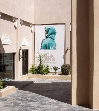 An arch, brick floor and sand-coloured walls leading to the entrance of Katara Gallery with a poster on display