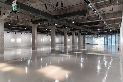 A long shot of the Garage Gallery showcasing its industrial ceiling, grey cement pillars and spotlights