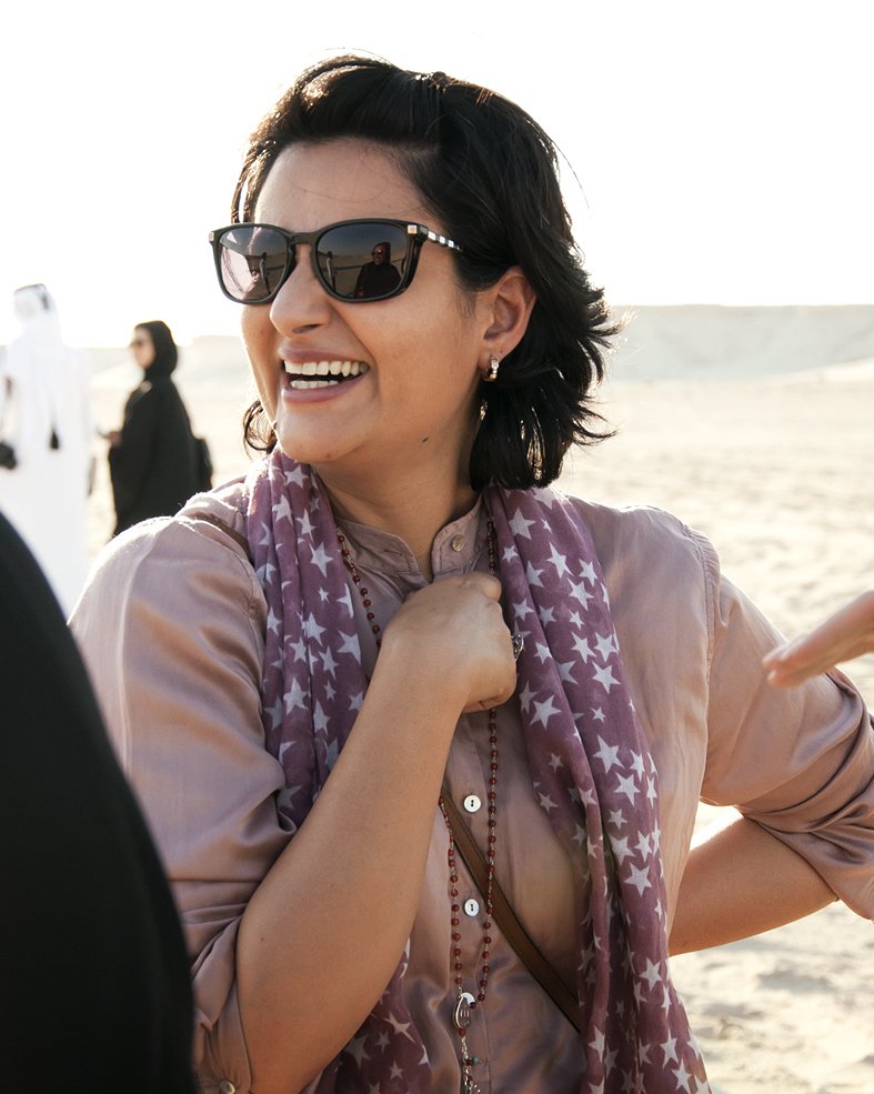 Portrait of Hala Mohammed Al Khalifa smiling and talking to people in a desert background