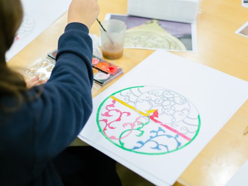 A child painting inside the lines of an Islamic design on paper