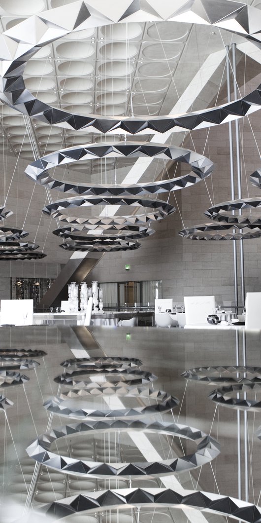 A dramatic view of Idam restaurant showing large circular ceiling lights and their reflection in a mirrored surface