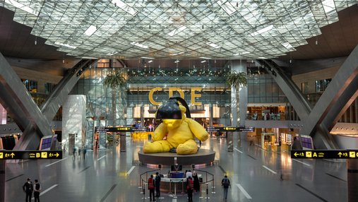 A sculpture of a  yellow teddy with a lamp above its head at Hamad International Airport