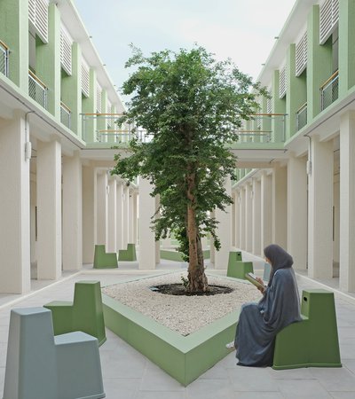 An open air courtyard, with contemporary seating and a woman reading.