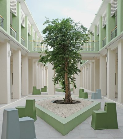 Exterior view of a courtyard with a tree and modern seating.
