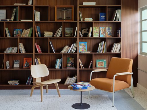 Interior view of a seating area in Liwan's library with two chairs, small table and bookshelves in the background.