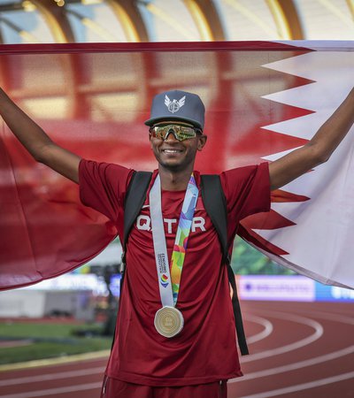 Athlete Mutaz Essa Barshim holding a Qatari flag after a victory